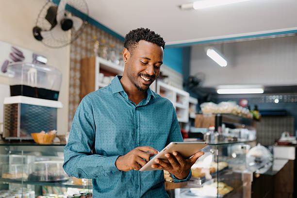 Small business owner smiling while checking a tablet in his shop