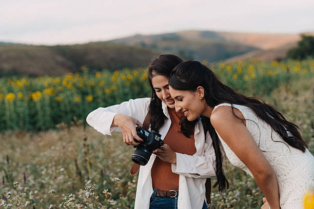 photographer shares photo on camera with client in  green mountainous landscape  