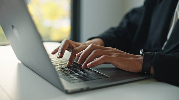 Hands typing on a laptop at a desk